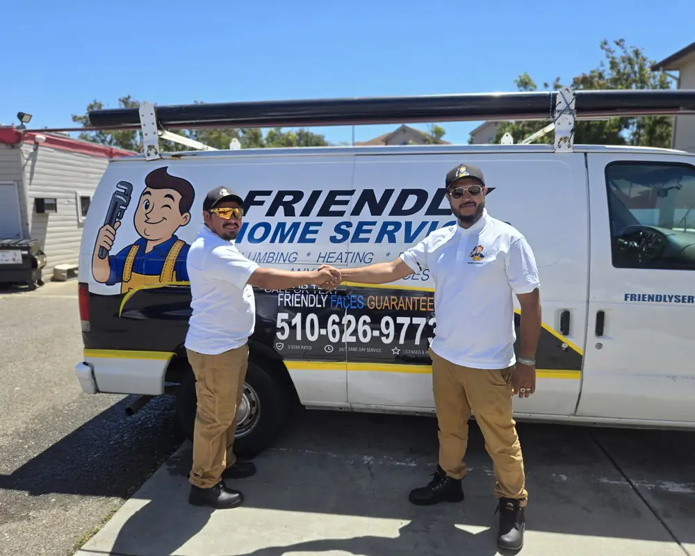 Two Friendly Services plumbers shaking hands next to a company van